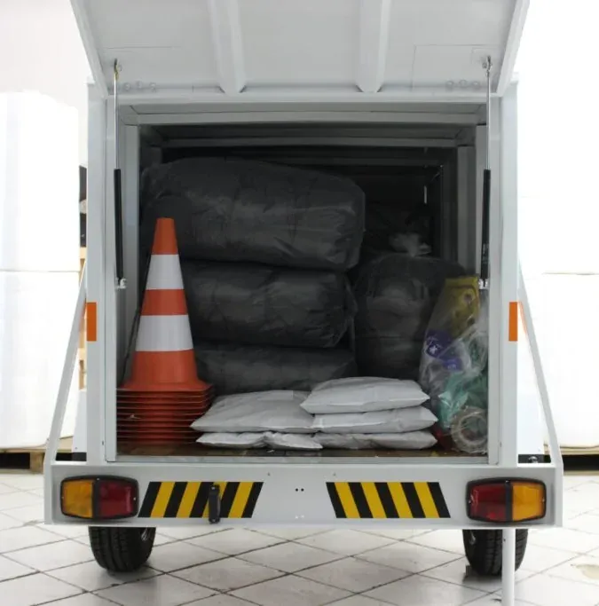 Traseira aberta da carretinha de emergência, com cone de sinalização e sacos de absorvente