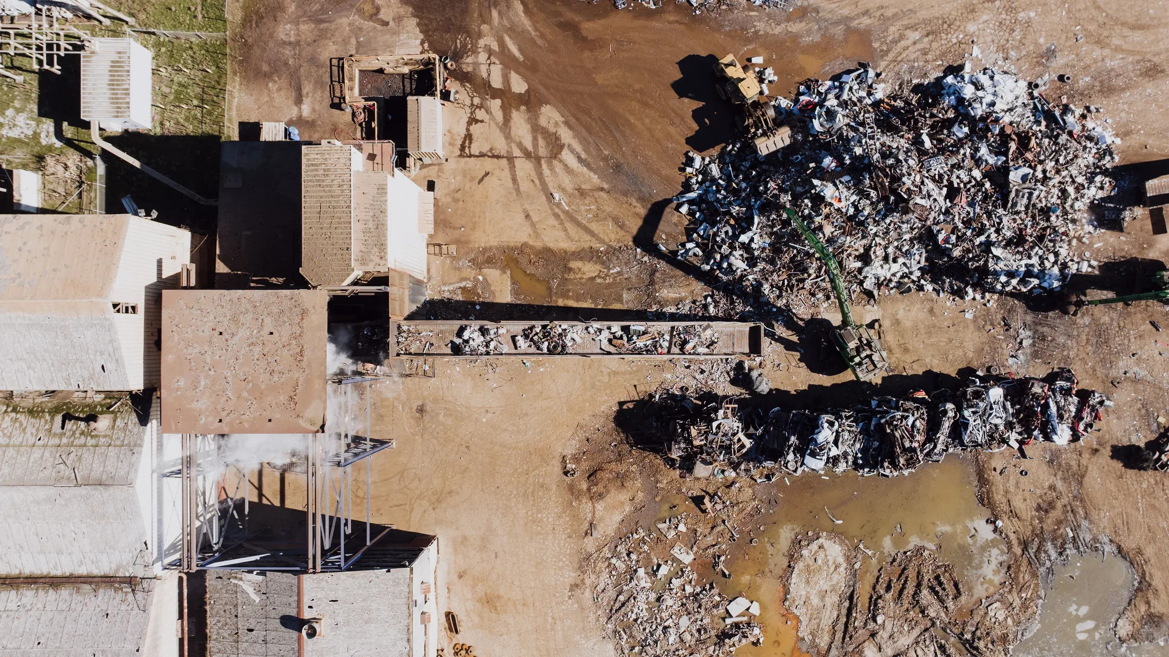 Vista aérea de uma área industrial com manchas escuras de resíduo espalhadas pelo solo entre estruturas de concreto